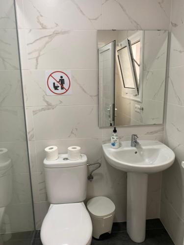 La salle de bains blanche est pourvue de toilettes et d'un lavabo. dans l'établissement Mirador del muelle house, à Orzola
