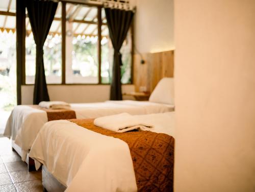 a hotel room with three beds and a window at Pondok Tingal Borobudur in Magelang