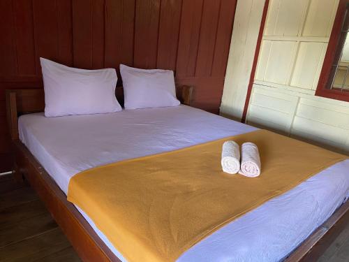 a bed with two white slippers on top of it at Souksanh Guesthouse in Ban Donsôm