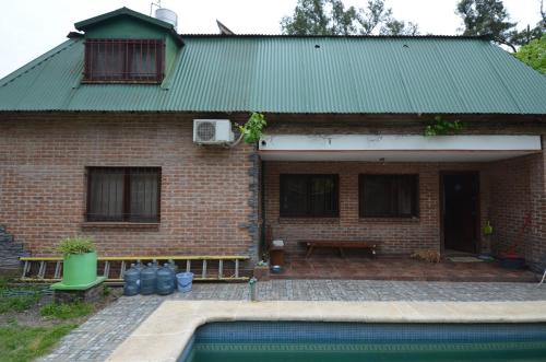 una casa de ladrillo con piscina frente a ella en Hostel Aeropuerto Ezeiza en Monte Grande