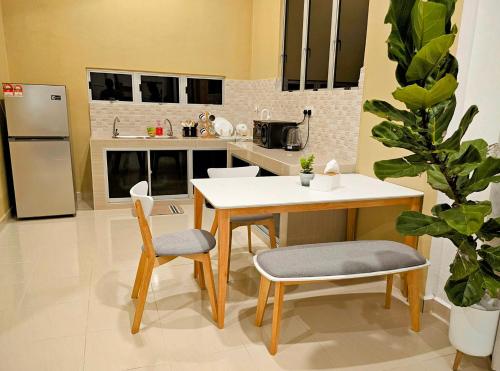 cocina con mesa, 2 sillas y nevera en Homestay Rumah Tengok Jelawat Bachok, en Bachok