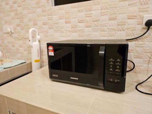 a black microwave sitting on top of a counter at Homestay Rumah Tengok Jelawat Bachok in Bachok