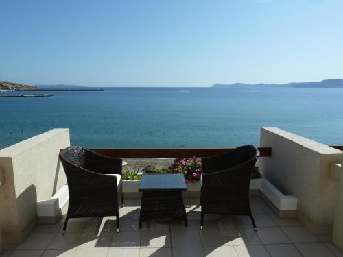 a table and chairs on a balcony overlooking the ocean at Sitia Bay in Sitia