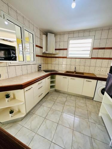 a kitchen with white cabinets and a tile wall at Résidence Lacolombe in Petit-Canal