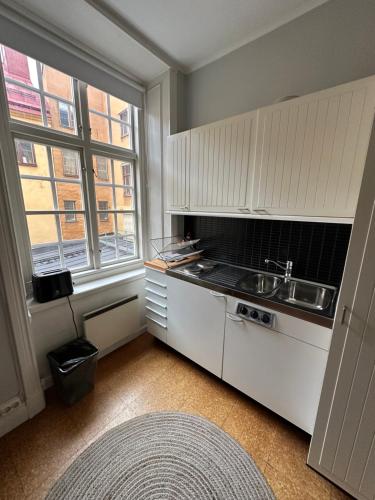 a kitchen with white cabinets and a sink and a window at Gamla Stan in Stockholm