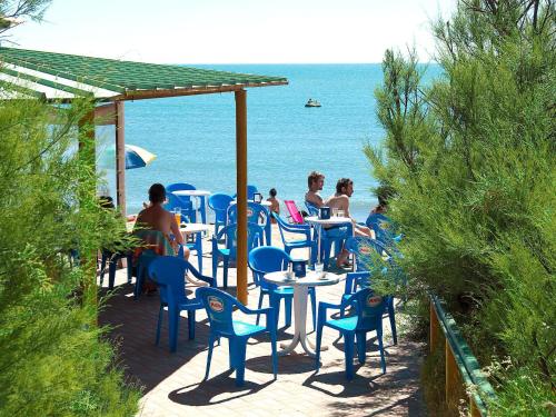 a group of people sitting at tables on the beach at Holiday Home Rosapineta Camping Village-3 by Interhome in Rosapineta