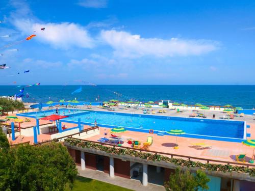 a large swimming pool next to the ocean at Holiday Home Rosapineta Camping Village-3 by Interhome in Rosapineta