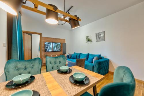 a living room with a table and blue chairs at Apartman Zelenbor 4 Vila Zlatibor Luxury&Spa in Zlatibor