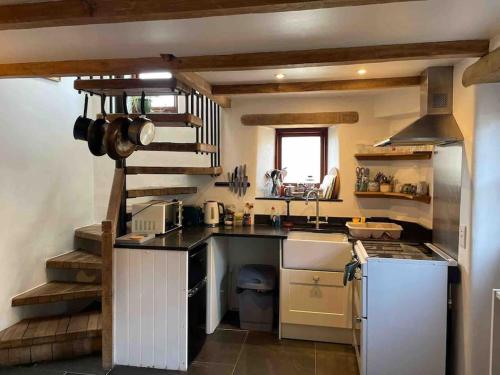 a kitchen with a sink and a stove top oven at 9A Viaduct Cottage - the cosiest bolthole in the SW! in Hayle