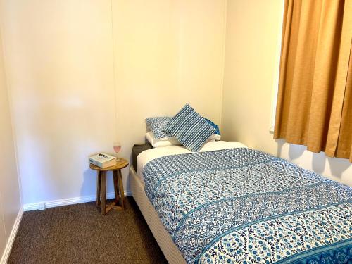 Dormitorio pequeño con cama y mesa auxiliar en Selwyn Cottage 3, en Tumbarumba