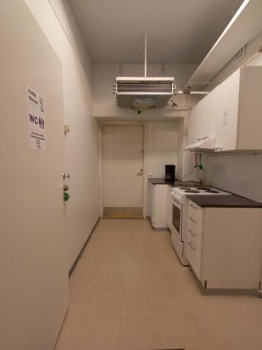 a kitchen with white appliances and a long hallway at Hotelli Posti in Äänekoski