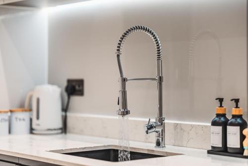 a kitchen sink with water pouring from a faucet at Luxurious 3 Bed Home, Free Parking in Manchester