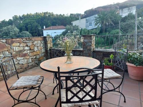 una mesa y sillas en un patio con una pared de piedra en El Descanso de Las Hurdes, 