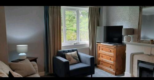 a living room with a tv and a chair and a fireplace at Wingfield House 3 Bed in Greasbrough