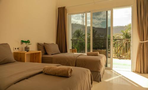 a hotel room with two beds and a balcony at The Peak Surf House in Huu