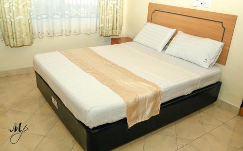 una camera da letto con un grande letto con lenzuola bianche di Mei Place Apartments a Mombasa