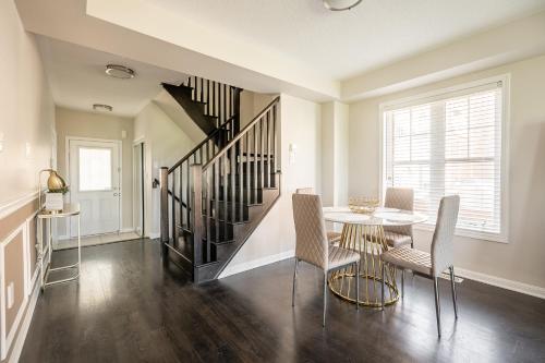 a dining room with a table and chairs and a staircase at GLOBALSTAY Modern 3 Bedroom House in Brampton in Brampton