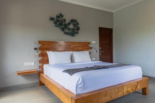 - une chambre avec un grand lit et une tête de lit en bois dans l'établissement Belle Asana, à Canggu