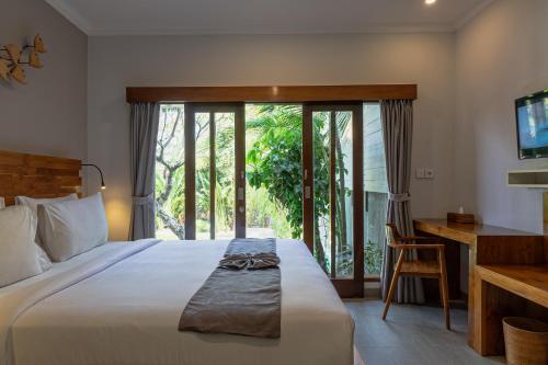 a bedroom with a bed and a desk and a window at Belle Asana in Canggu