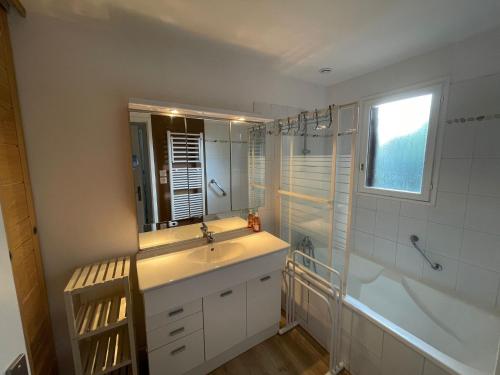 une salle de bain avec un lavabo, une baignoire et un miroir dans l'établissement Cabane C60, à Lège-Cap-Ferret