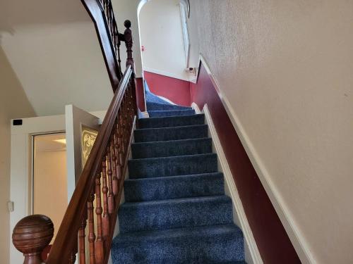 - un escalier dans un bâtiment doté d'une moquette bleue dans l'établissement Victoria Guest House, à Stoke-on-Trent