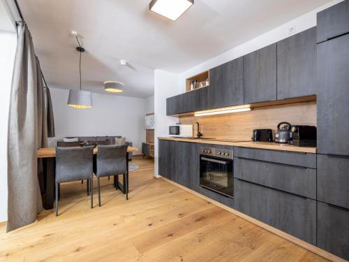 a kitchen with black cabinets and a table with chairs at Apartment Comfort Bergblick 04 by Interhome in Söll