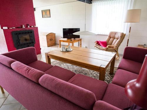 a living room with a purple couch and a fireplace at Holiday Home Thara - 100m from the sea in SE Jutland by Interhome in Sønderby