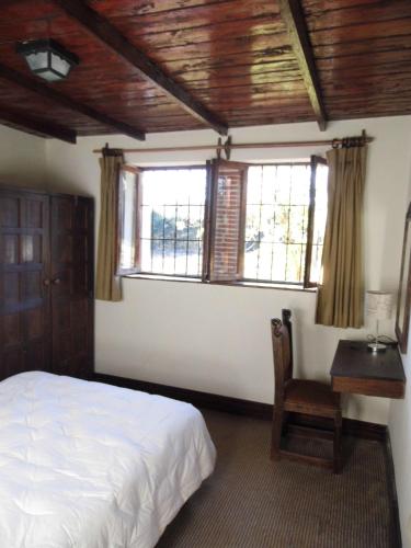a bedroom with a bed and a desk and windows at Inka Tambo Hacienda in Cusco