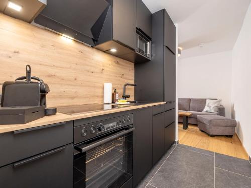 a kitchen with black cabinets and a stove at Apartment Kleines Bergblick 15 by Interhome in Söll