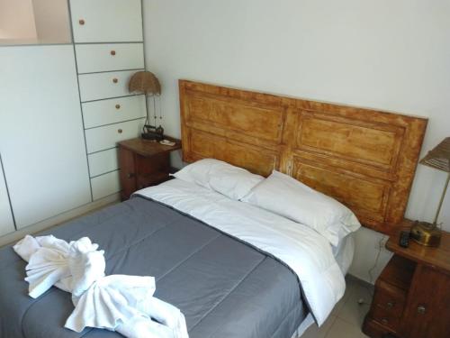 Una cama con cabecero de madera y sábanas y almohadas blancas. en TAMBO LIBERTADOR, en San Juan