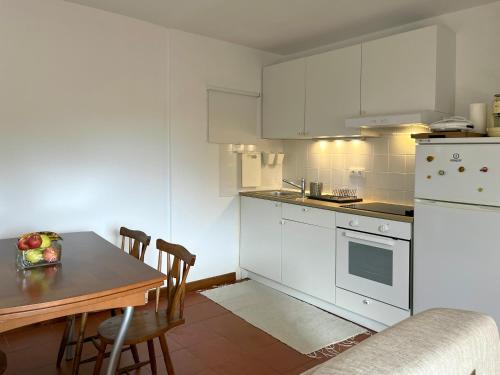 a kitchen with white appliances and a table with chairs at Casa do Tanque in Vila Nova de Famalicão