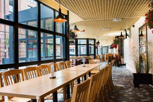 a restaurant with wooden tables and chairs and windows at Browar Lubicz Free GARAGE in Kraków