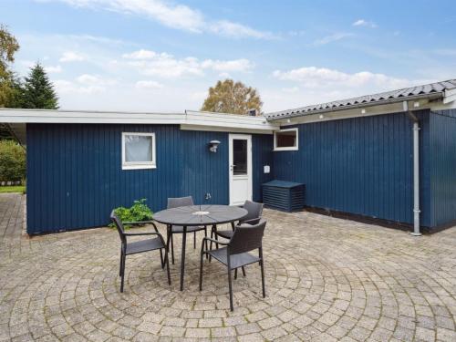 un patio con mesa y sillas frente a un edificio azul en Holiday Home Ilsebil - 250m from the sea in SE Jutland by Interhome, en Juelsminde
