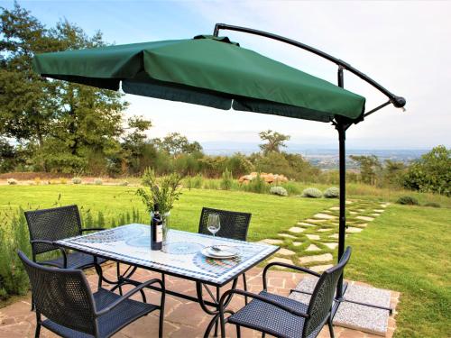 einen Tisch und Stühle unter einem grünen Schirm in der Unterkunft Holiday Home Cignella Resort by Interhome in Osteria Delle Noci