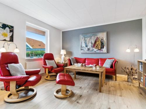 a living room with red chairs and a table at Holiday Home Ravn - 3-3km from the sea in Bornholm by Interhome in Vester Sømarken
