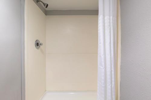 a shower with a white shower curtain in a bathroom at Clarion Hotel & Suites BWI Airport North in Baltimore