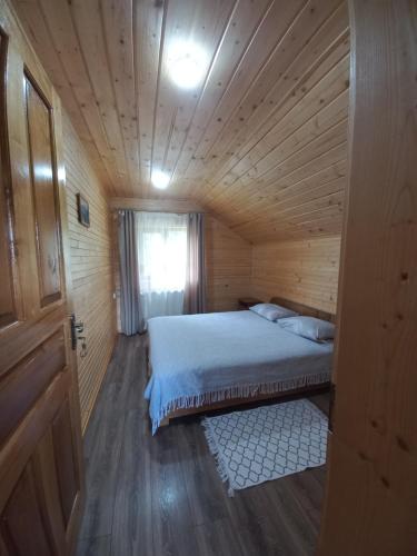ein Schlafzimmer mit einem Bett in einer Holzhütte in der Unterkunft На горі in Worochta