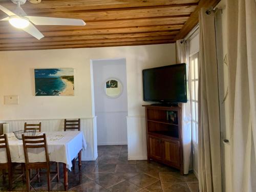 ein Esszimmer mit einem Tisch und einem Flachbild-TV in der Unterkunft Saint Leu - Gîte Ylang Ylang - Bardzour in Saint-Leu