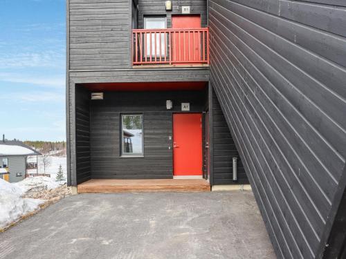 a black house with a red door and a balcony at Holiday Home Skivillas 47 ukkohalla - a1 by Interhome in Hyrynsalmi