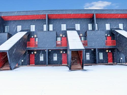 a row of buildings with red doors in the snow at Holiday Home Skivillas 47 ukkohalla - a3 by Interhome in Hyrynsalmi