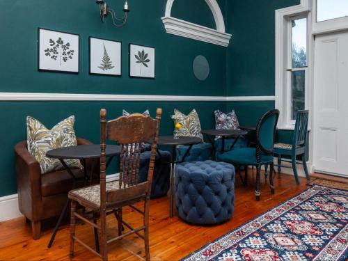 ein Esszimmer mit grünen Wänden, Tischen und Stühlen in der Unterkunft Belvedere House in Kapstadt