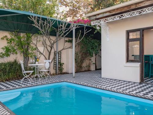 einen Pool vor einem Haus mit einem Tisch und Stühlen in der Unterkunft Belvedere House in Kapstadt