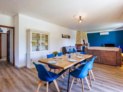 a dining room with a wooden table and blue chairs at Holiday Home L'Aouzet by Interhome in Uzès