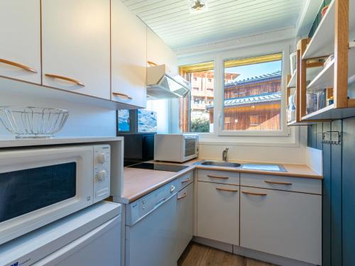une cuisine avec des armoires blanches et un micro-ondes dans l'établissement Apartment Les Grandes Balmes I et II - Le Lac-11 by Interhome, à Tignes