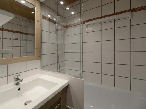 une salle de bain avec un lavabo, une baignoire et un miroir dans l'établissement Studio divisible au pied des pistes avec balcon et casier à skis - FR-1-181-2083, à La Plagne Tarentaise