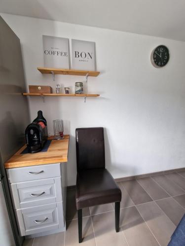 a desk with a chair and a clock on a wall at FeWo mit großer Terrasse im Herzen der fränkischen Schweiz in Unterleinleiter