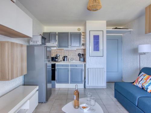 un salon avec un canapé bleu et une cuisine dans l'établissement Apartment Les Marines d'Aryana-4 by Interhome, à Six-Fours-les-Plages