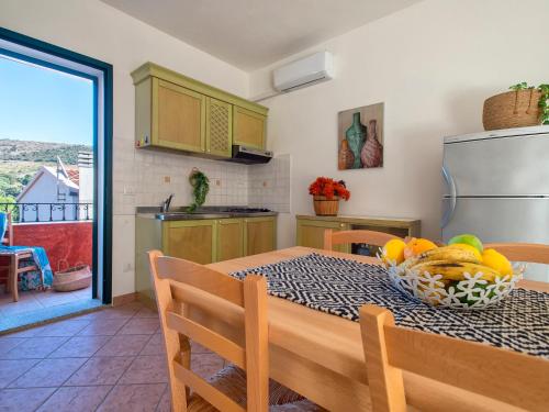 una cucina con tavolo e ciotola di frutta di Apartment L'Oasi Trilo A6 by Interhome a Trinità dʼAgultu