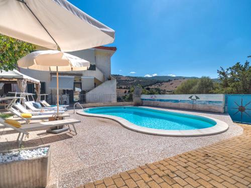 a swimming pool with an umbrella and chairs and a table at Apartment L'Oasi Trilo A6 by Interhome in Trinità dʼAgultu
