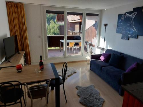 un salon avec un canapé bleu et une table dans l'établissement Confortable studio avec balcon à Pra-Loup - FR-1-165A-167, à Uvernet